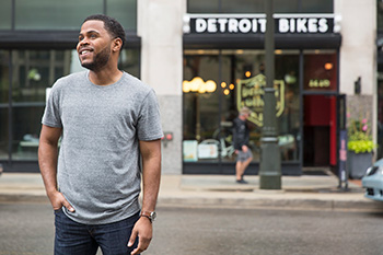Student standing infront of Detroit shops smiling