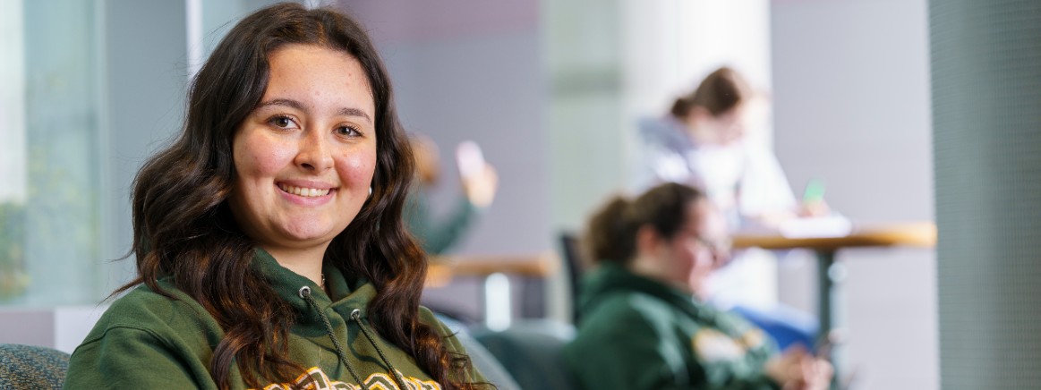 female student smiling and wearing green wayne state university sweatshirt
