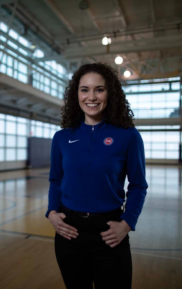 Jenae Lodewyk standing on a basketball court wearing a Detroit Pistons shirt