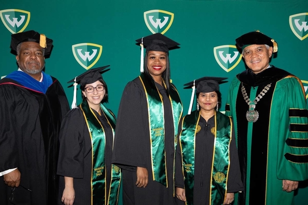 Wayne State University graduates posing with Provost Keith Whitfield and President M. Roy Wilson