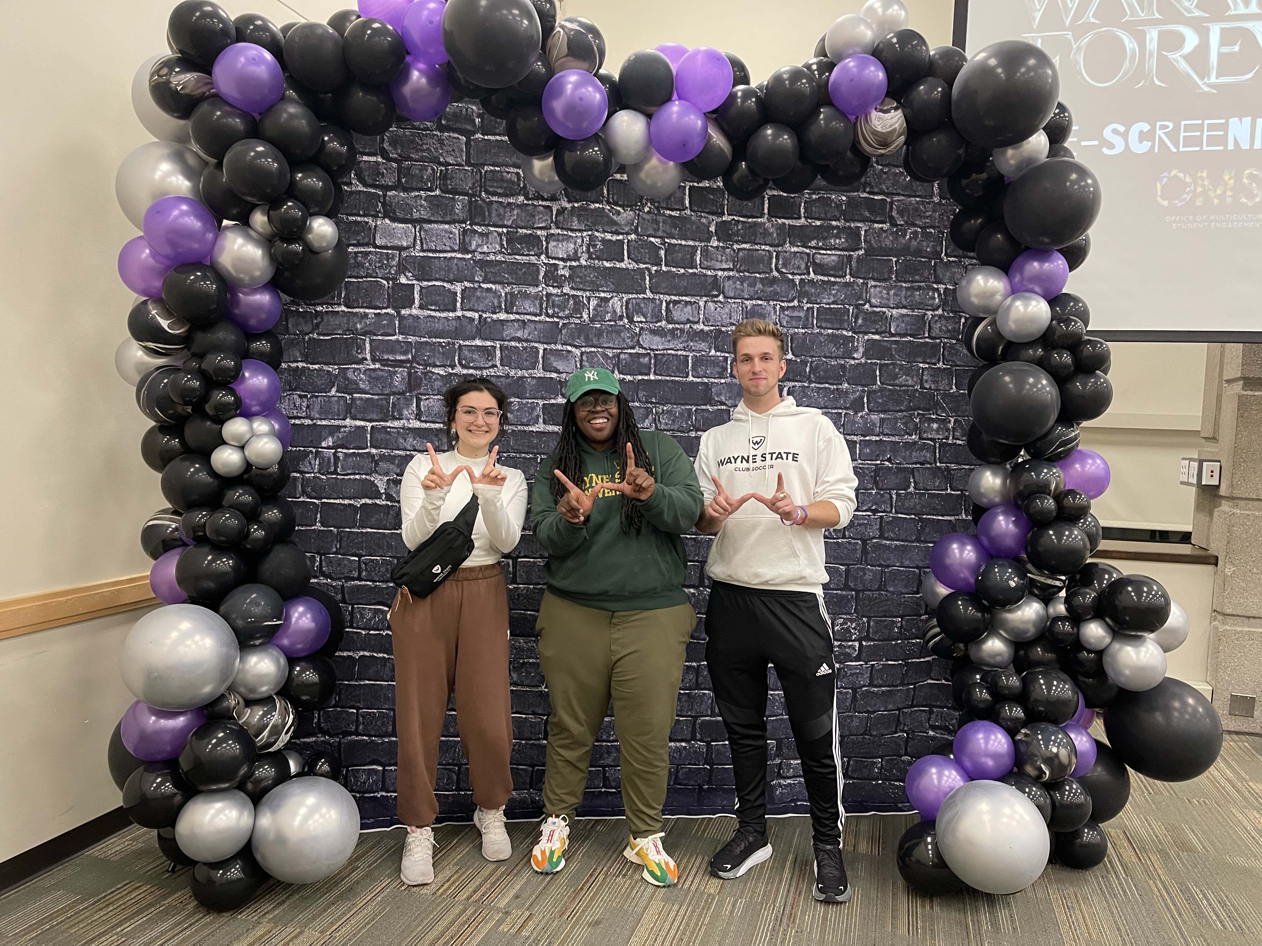 Students and director standing under a ballon arch